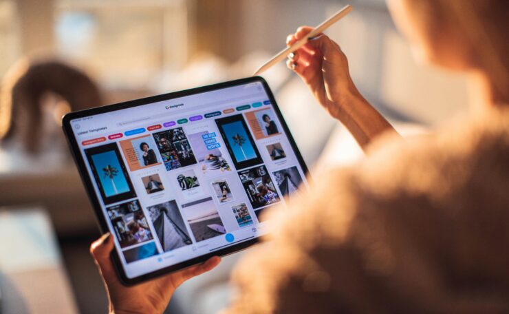 A person uses a digital tablet with a stylus indoors in a warm, cozy setting.